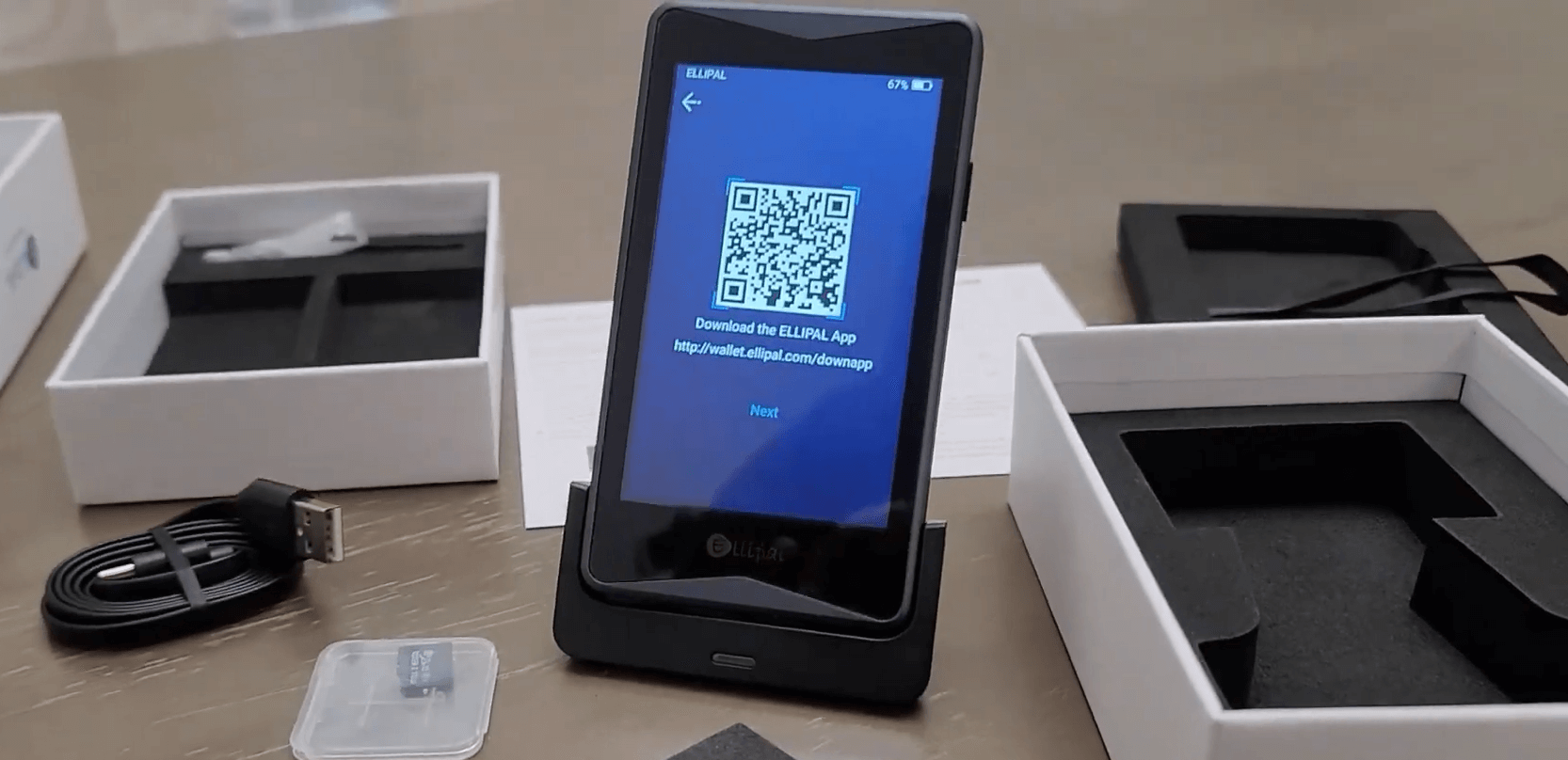 Ellipal Titan wallet showing a QR code on its screen, next to a smartphone.